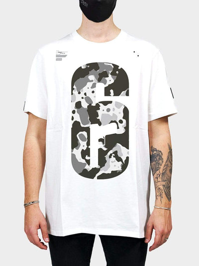 White T-shirt with a camo print from the game Rainbow 6. Model wears a face mask aswell.